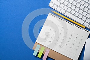 Calendar, keyborad on the blue table background, planning for business meeting or travel planning concept