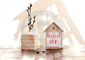 Calendar for March 1: a decorative house with the name of the month March in English, numbers 01, a bouquet of flowering willow in
