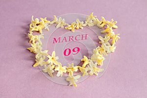 Calendar for March 9: numbers 09, the name of the month of March in English in a heart made of yellow hyacinth flowers, pastel