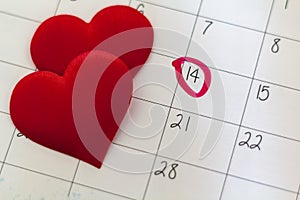 Calendar with marked 14th february date and red heart shaped chocolate candies