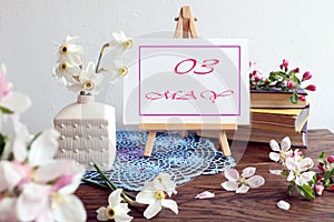 Calendar for May 3 : an easel with an inscription - the name of the month of May in English, the numbers 03, a bouquet of