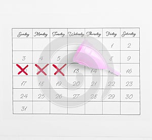 Calendar and menstrual cup on white background. Gynecological care