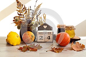 Calendar for November 24 : the name of the month in English, the number 24 , a bouquet of dried flowers in a basket, pumpkins,