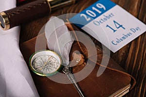 Calendar with October 14 date near leather notebook with nib and compass