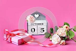 Calendar for October 5 : the name of the month in English, the numbers 05, delicate roses, a packed gift tied with a pink ribbon