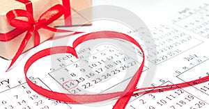 Calendar page with mark valentines day in red circle. February inside heart-shaped ribbon. Handmade gift box wrapped
