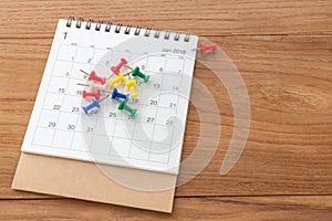 Calendar with pins wooden background