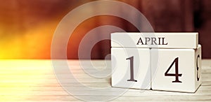 Calendar reminder event concept. Wooden cubes with numbers and month on April 14 with sunlight