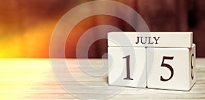 Calendar reminder event concept. Wooden cubes with numbers and month on July 15 with sunlight