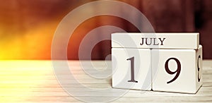 Calendar reminder event concept. Wooden cubes with numbers and month on July 19 with sunlight