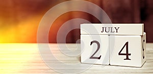 Calendar reminder event concept. Wooden cubes with numbers and month on July 24 with sunlight