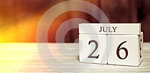 Calendar reminder event concept. Wooden cubes with numbers and month on July 26 with sunlight