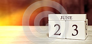 Calendar reminder event concept. Wooden cubes with numbers and month on June 23 with sunlight