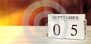 Calendar reminder event concept. Wooden cubes with numbers and month on September 5 with sunlight