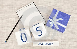 Calendar with trendy blue text and numbers for January 5 and a gift in a box