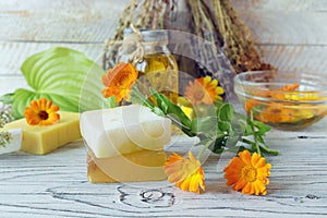 Calendula flowers, soap, oils and tinctures, on a wooden background, natural ingredients