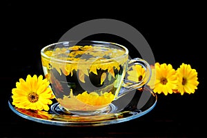 Calendula tea in transparent cup isolated on black