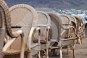 Caleta de Famara/SPAIN - February 2, 2018: Chairs and tables of an empty outdoor restaurant with the sea in the background photo