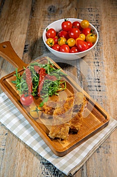 Calf escutcheon recipe for Milanese, Parmesan, Roquette and candied tomatoes