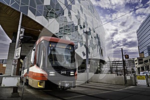 A light rail transit train exits a tunnel from under the central downtown public library.