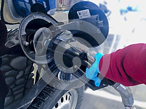 A person wearing single use gloves, pumping gasoline to a chevrolet SUV vehicle during the