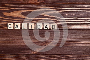 Calidad, quality spanish word, lettering on wooden background photo