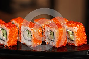 California rolls with orange masago caviar on a glossy black plate