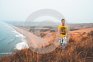 Young man exploring California by the ocean at Point Reyes cliffs.