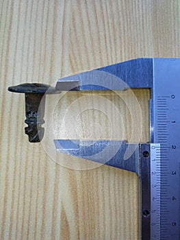 Caliper measures the screw on the wooden board