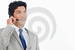 Asian man wearing light gray suit blue tie adjusting headset while smiling in studio, copy space
