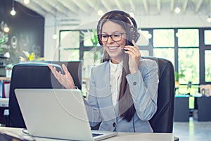 Call center agent woman with headset using laptop and talking to a client via online customer support service