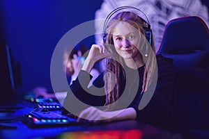 Call center beautiful girl operator professional gamer smiling and talking into a microphone, dark blue neon background