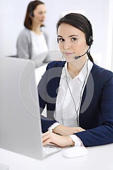 Call center. Beautiful woman sitting and working in headset at customer service office. Business concept