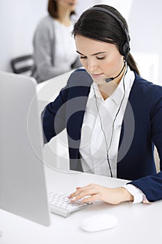 Call center. Beautiful woman sitting and working in headset at customer service office. Business concept