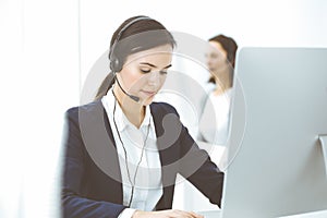 Call center. Beautiful woman sitting and working in headset at customer service office. Business concept
