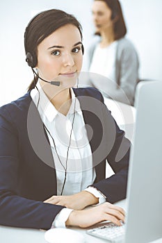 Call center. Beautiful woman sitting and working in headset at customer service office. Business concept