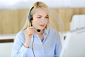 Call center. Blonde business woman sitting in headset at customer service office. Concept of telesales business or home