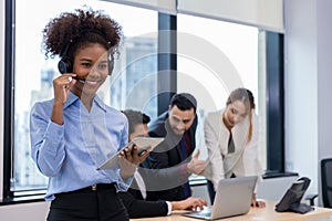 Call center business woman talking on headset. Call center worker accompanied by her team. Customer service executive working at o