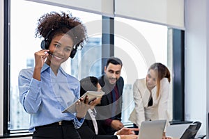 Call center business woman talking on headset. Call center worker accompanied by her team. Customer service executive working at o