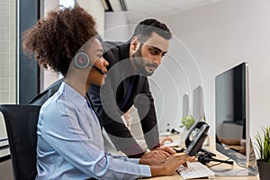 Call center business woman talking on headset. Call center worker accompanied by her team. Customer service executive working at o