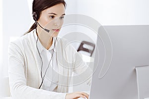 Call center. Casual dressed woman sitting in headset at customer service office. Group of operators at work. Business