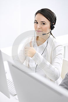 Call center. Casual dressed woman sitting and working in headset at customer service office. Business concept