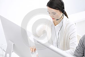 Call center. Casual dressed woman sitting and working in headset at customer service office. Business concept