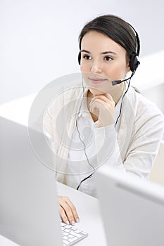 Call center. Casual dressed woman sitting and working in headset at customer service office. Business concept