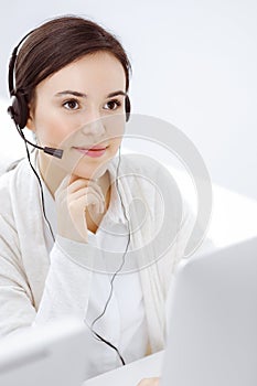 Call center. Casual dressed woman sitting and working in headset at customer service office. Business concept