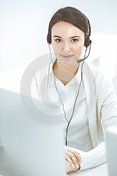 Call center. Casual dressed woman sitting and working in headset at customer service office. Business concept