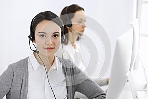 Call center. Casual dressed woman working in headset with diverse colleagues at office. Business concept