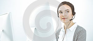 Call center. Casual dressed woman working in headset with diverse colleagues at office. Business concept