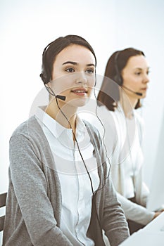Call center. Casual dressed woman working in headset with diverse colleagues at office. Business concept