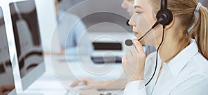 Call center. Group of casual dressed operators at work. Blond business woman in headset at customer service office